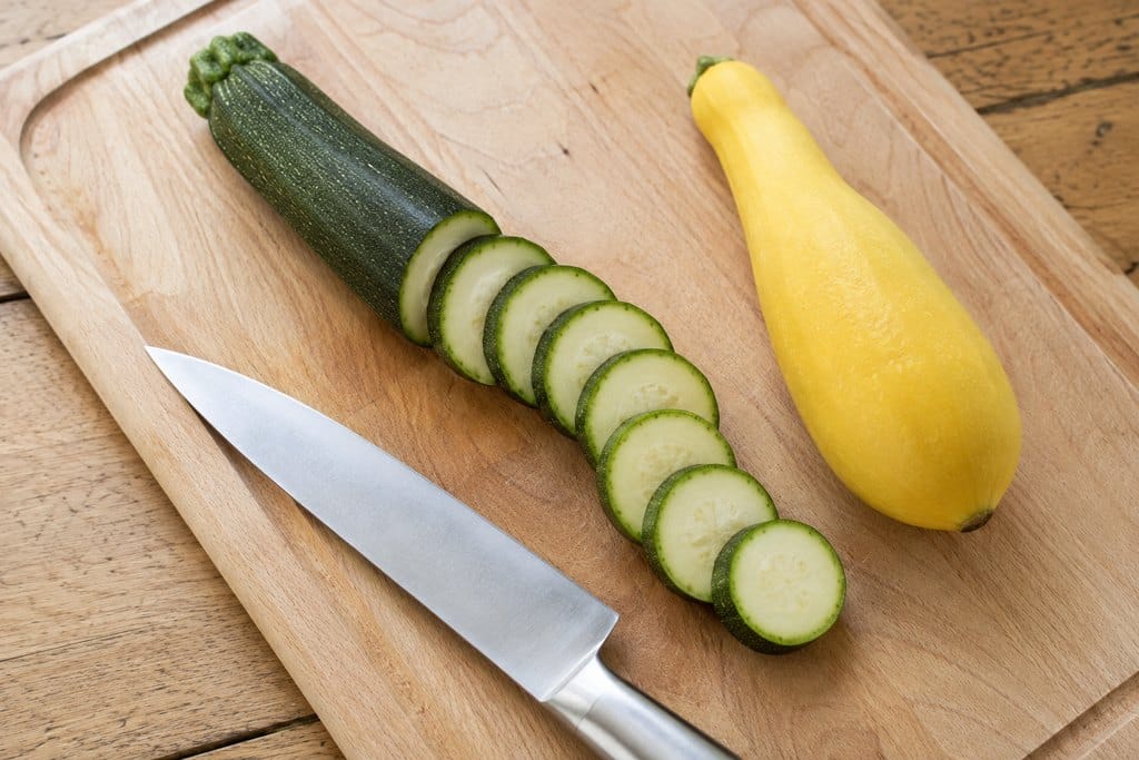 Green zucchini and yellow summer squash cut into even rounds on a cutting board
how to freeze zucchini