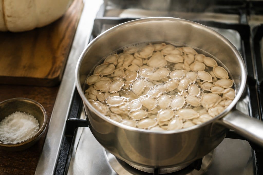 Pumpkin seeds simmering in a saucepan of water