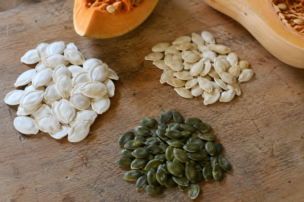 Pumpkins of different sizes with pale shell-on seeds and green pepitas